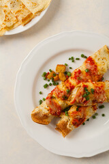 Baked pancakes with chicken in tomato sauce.