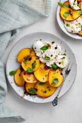 Italian Caprese salad with peaches, buratta cheese, herbs and balsamico creme. Fresh gourmet salad...