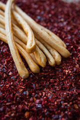 Baking edible bread crunchy grissini sticks lie on the sliced spice of red savory hot pepper close-up vertical frame