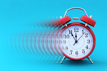 Red alarm clock stands on a blue background.