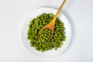 Pickled green peas on a white plate on a white background