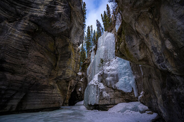 Fototapeta na wymiar view from inside maligne river canyon on frozen waterfall with blue water