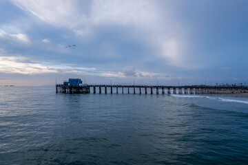 Obraz premium Drone shot of a metallic pier of the sea under the cloudy sky, cool for background