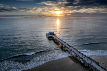 Picturesque view of a sandy beach with a wooden pier stretching out into the bright blue ocean