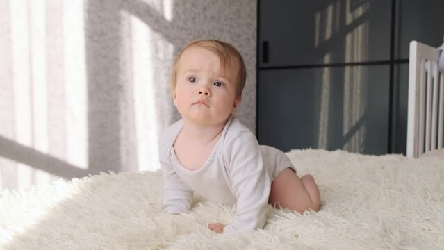 Adorable baby girl crawling on a bed at home. Happy infant 9 months old learning having fun enjoying childhood at home