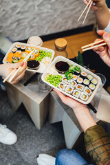 People having lunch, group of friends having sushi, eating asian food.