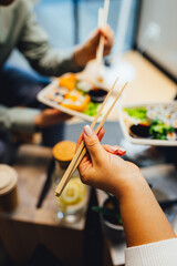 Fototapeta premium People having lunch, group of friends having sushi, eating asian food.