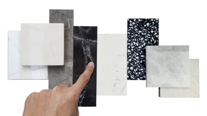 close up designer's hand picking interior premium stone samples including black marble, grey artificial stone, terrazzo tiles placed with floor tiles isolated on background with clipping path.