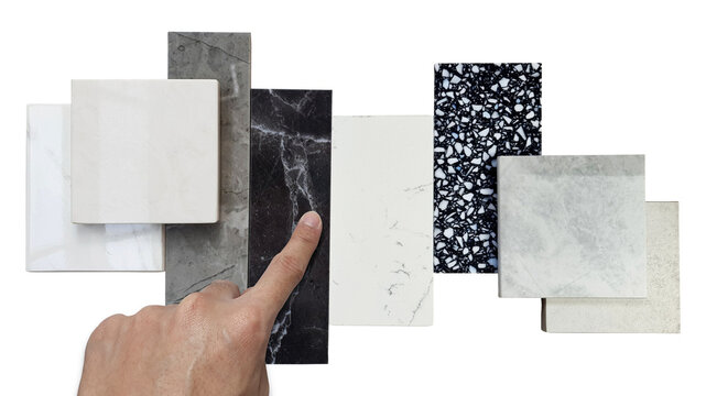 Close Up Designer's Hand Picking Interior Premium Stone Samples Including Black Marble, Grey Artificial Stone, Terrazzo Tiles Placed With Floor Tiles Isolated On Background With Clipping Path.