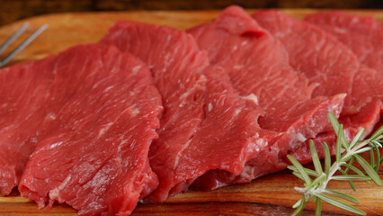  plusieurs steaks de boeuf crus, en gros plan, sur une planche à découper