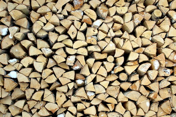  Woodpile of stacked birch firewood with snow in winter.	