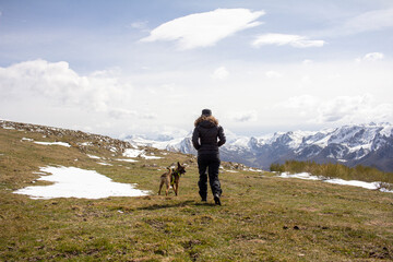 Fototapeta premium woman walking with her dog through the mountains of Somiedo, Asturias in winter, with the Picos de Europa in the background