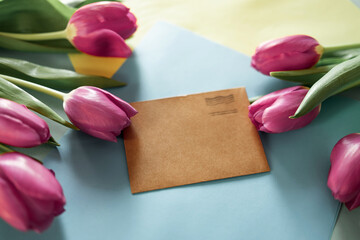 Spring mockup with blue blank paper list and pink tulip flowers on yellow background top view. Beautiful floral composition for design. Flat lay