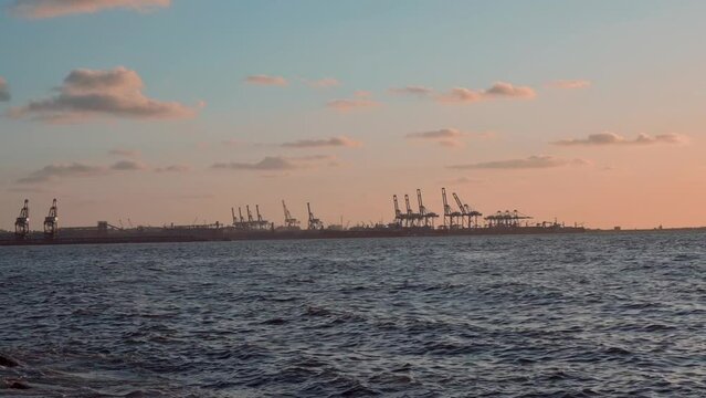 Slow motion of the calm Mediterranean Sea with the golden sunset and a ship port in the background