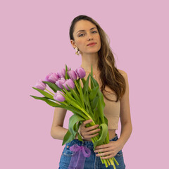 Beautiful young woman with a bouquet of lilac tulips on an isolated pink background. Copy space