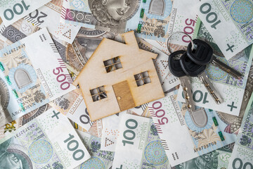 Mortgage or loan concept. Wooden model house and keys on polish złoty money, PLN zloty banknotes. Buying a home, flat or apartment in Poland.