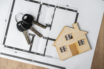 Home floor plans or building blueprint project, wooden model house and keys. Buying a home, flat or apartment. Architect, interior designer or real estate agent concept.