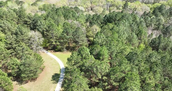 Flying over a park with paved paths through the woods in Macon, Georgia and sighting piles of downed trees from logging operations in a deforested clear-cut area across the Ocmulgee River