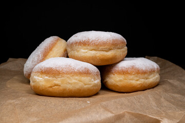 Polish pączki deep-fried doughnuts. Celebrating Fat Thursday, Tłusty czwartek feast, traditional day in Poland. Pączek food, powdered sugar topped and filled with rose hip jam.
