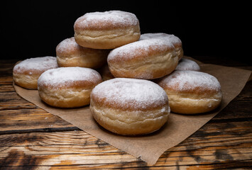 Polish pączki deep-fried doughnuts. Celebrating Fat Thursday, Tłusty czwartek feast, traditional day in Poland. Pączek food, powdered sugar topped and filled with rose hip jam.