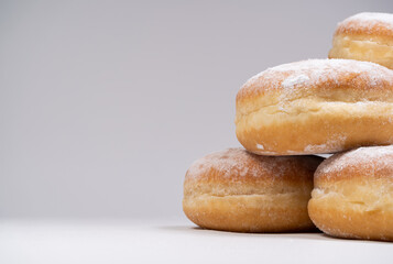 Polish pączki deep-fried doughnuts with copy space. Celebrating Fat Thursday (Tłusty czwartek) feast, traditional day in Poland. Pączek food, powdered sugar topped and filled with rose hip jam.