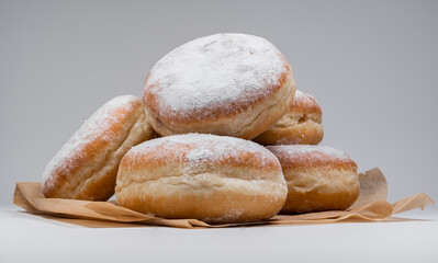 Polish pączki deep-fried doughnuts. Celebrating Fat Thursday, Tłusty czwartek feast, traditional day in Poland. Pączek food, powdered sugar topped and filled with rose hip jam.