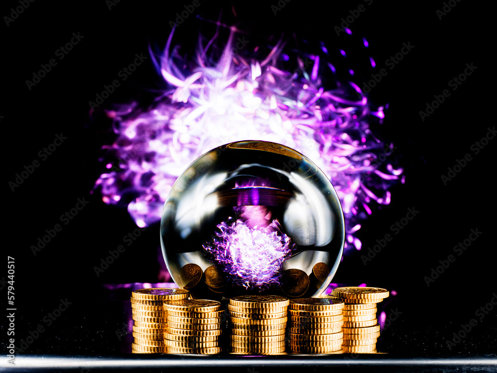 Wall mural crystal magical glass ball on stack of golden coins, abstract light painting on dark background. for