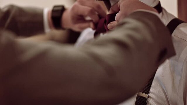 Slow-motion man tying a bowtie to a groom