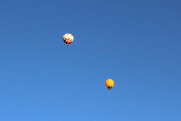 Two hot air balloons are visible against the blue sky.