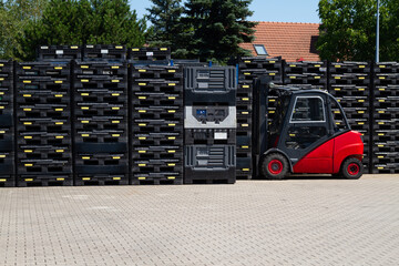 Forklift truck in warehouse with plastic pallets.