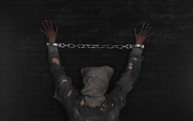 hands with prison chains, black brick wall