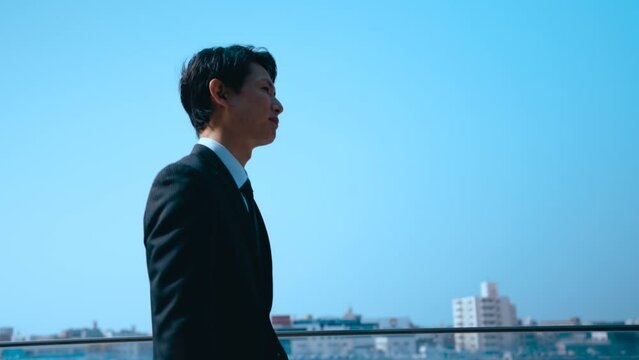 青空の下を颯爽と歩く日本人ビジネスマン