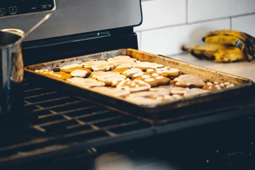 Tuinposter Baking tray with Christmas cookies on a gas stove. © Ben White/Wirestock Creators