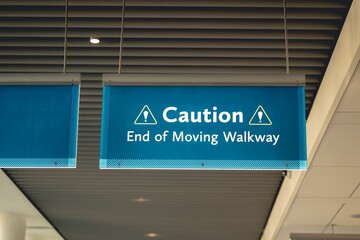 Hanging blue cation sign warning the end of a moving walkway