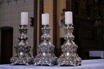 Three candles in candlesticks on a table in a Catholic church