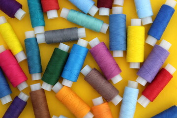 Background of multi-colored bright threads lying on a yellow background.	

