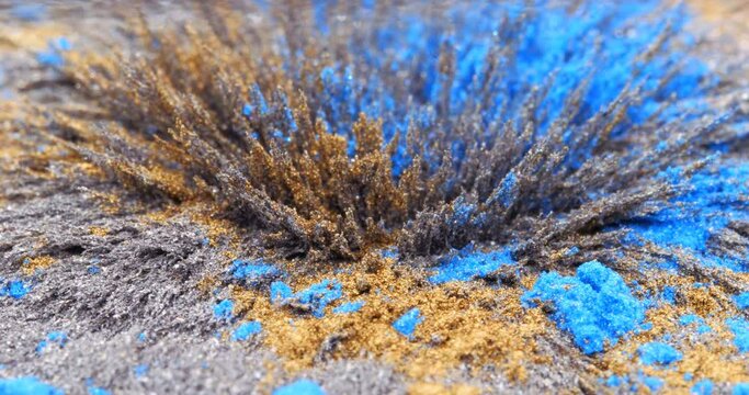 Yellow and blue metallic dust, chips, iron powder under the influence of a magnetic field. Abstract background. The surface is a color movable background. The natural phenomenon of magnetism.