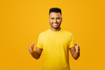 Young handsome Arab man measuring empty space, showing size standing isolated on yellow, cheerful...