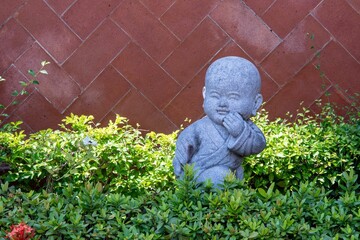 Baby Buddha statue in the garden surrounded by plants
