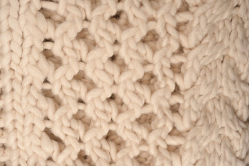 A fragment of beige knitted fabric, knitted from white sheep wool.