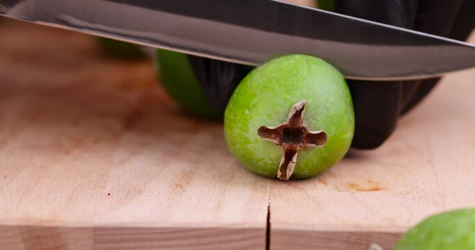 Green ripe feijoa cut in half on a board, half ripe feijoa with a soft sweet and sour filling