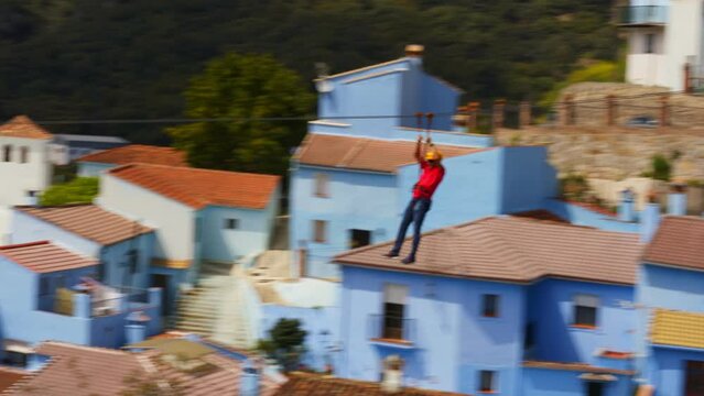 Person on a zip line over the Juzcar (Pueblos Blancos) in the Andalusia region, Spain