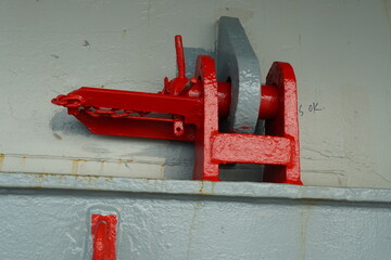 Red jumping stopper or securing cleat with chain used to secure movement of hatch covers of...