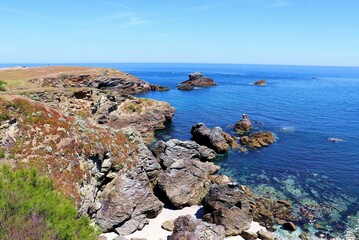 Beautiful view of huge rocks on a shore of a blue sea under the clear sky