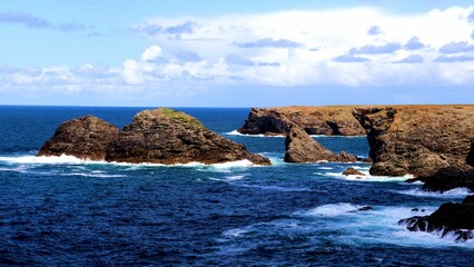 Fototapeta na wymiar Beautiful view of huge rocks on a shore of a blue sea under the clear sky