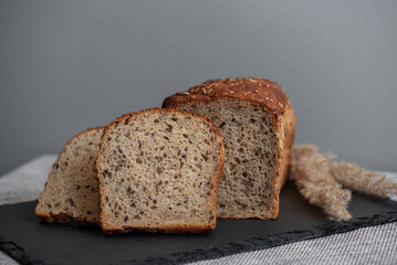 Rye bread with seeds lies on a dark board on a light table. My home bakery. Organic whole grain bread. Bio Dinkel Brot. Healthy bread. complex carbohydrates. health diet. Healthy breakfast.