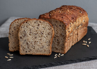 Rye bread with seeds lies on a dark board on a light table. My home bakery. Organic whole grain bread. Bio Dinkel Brot. Healthy bread. complex carbohydrates. health diet. Healthy breakfast.