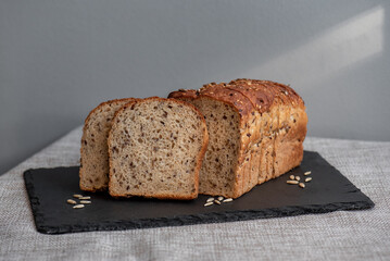 Rye bread with seeds lies on a dark board on a light table. My home bakery. Organic whole grain bread. Bio Dinkel Brot. Healthy bread. complex carbohydrates. health diet. Healthy breakfast.