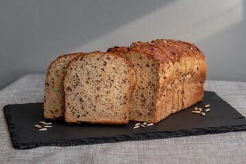 Rye bread with seeds lies on a dark board on a light table. My home bakery. Organic whole grain bread. Bio Dinkel Brot. Healthy bread. complex carbohydrates. health diet. Healthy breakfast.
