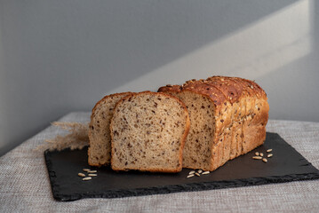 Rye bread with seeds lies on a dark board on a light table. My home bakery. Organic whole grain...